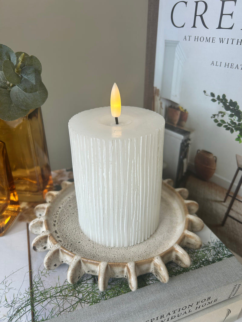 Round glass candle holder filled with dried flowers