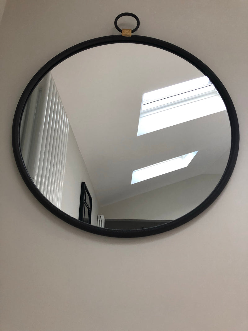 Black round mirror with gold accent and fob detail