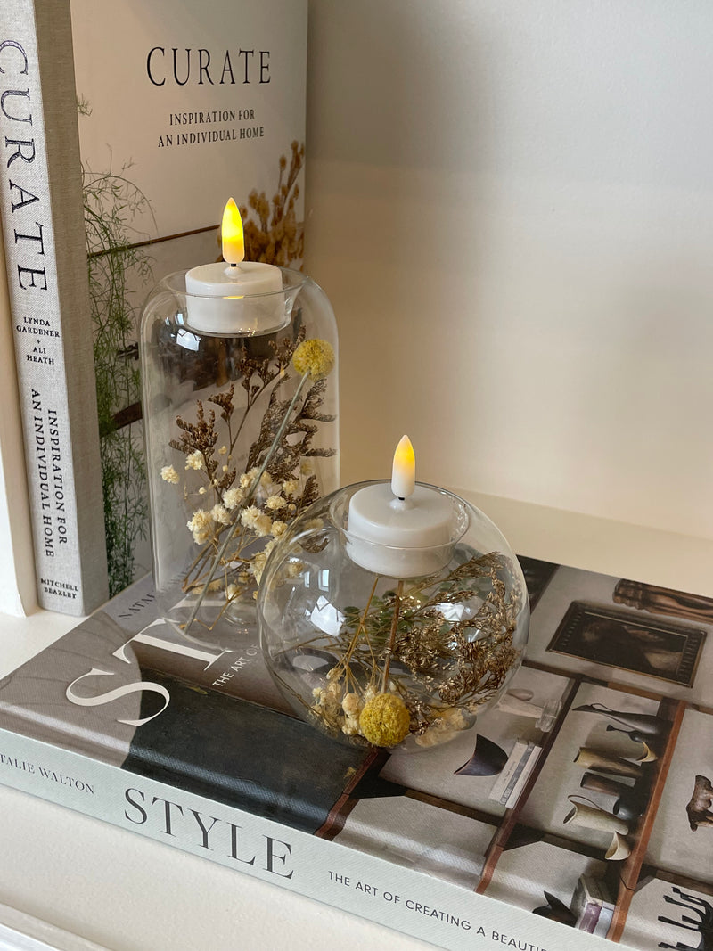 Round glass candle holder filled with dried flowers