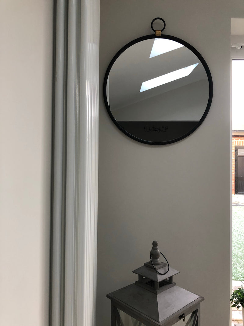 Black round mirror with gold accent and fob detail