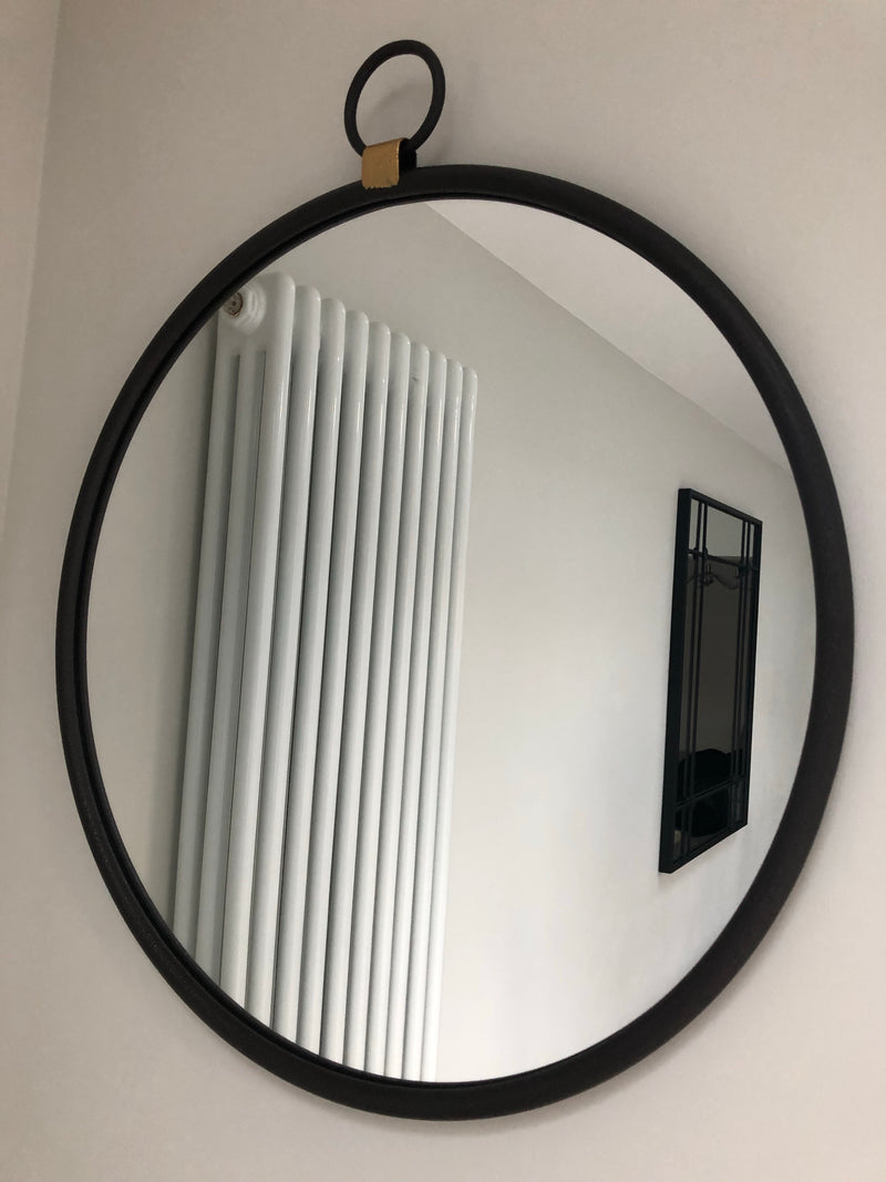 Black round mirror with gold accent and fob detail