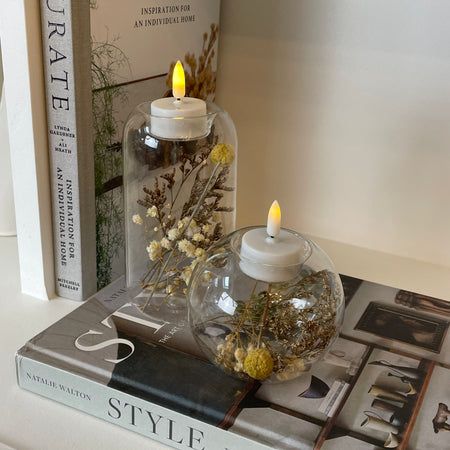 Round glass candle holder filled with dried flowers
