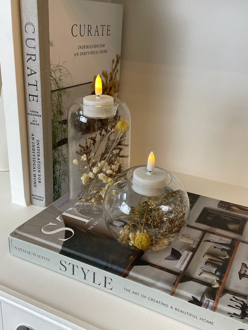 Round glass candle holder filled with dried flowers