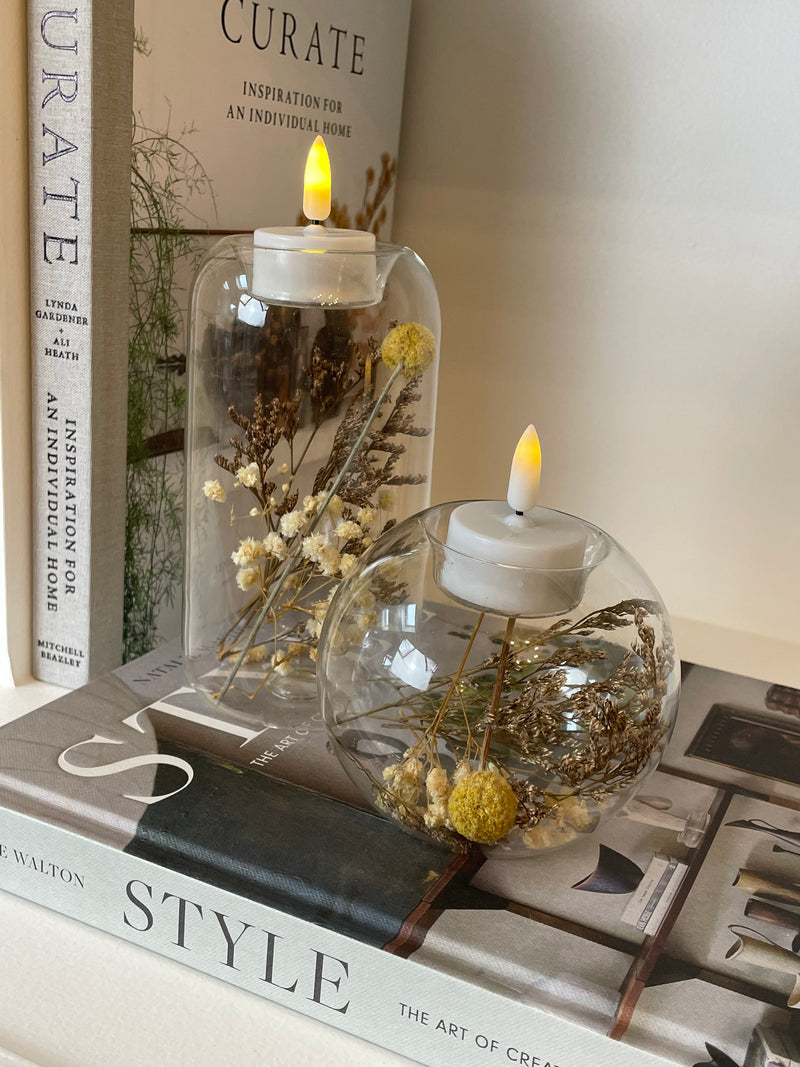 Round glass candle holder filled with dried flowers