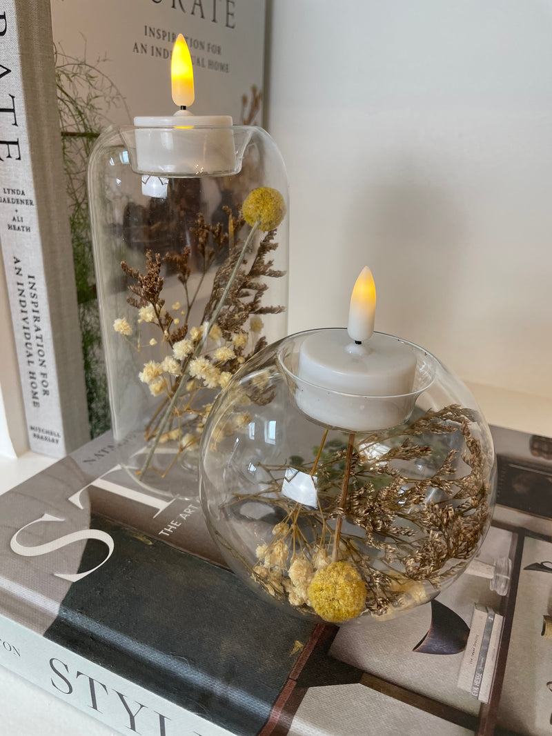 Round glass candle holder filled with dried flowers