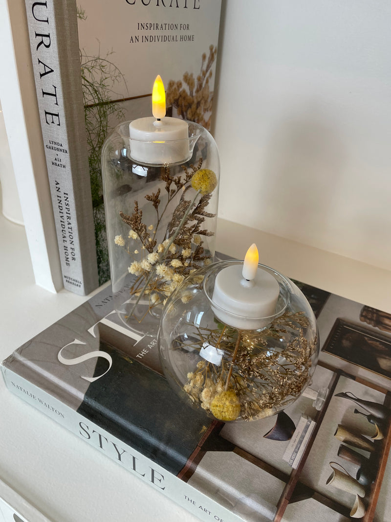 Round glass candle holder filled with dried flowers