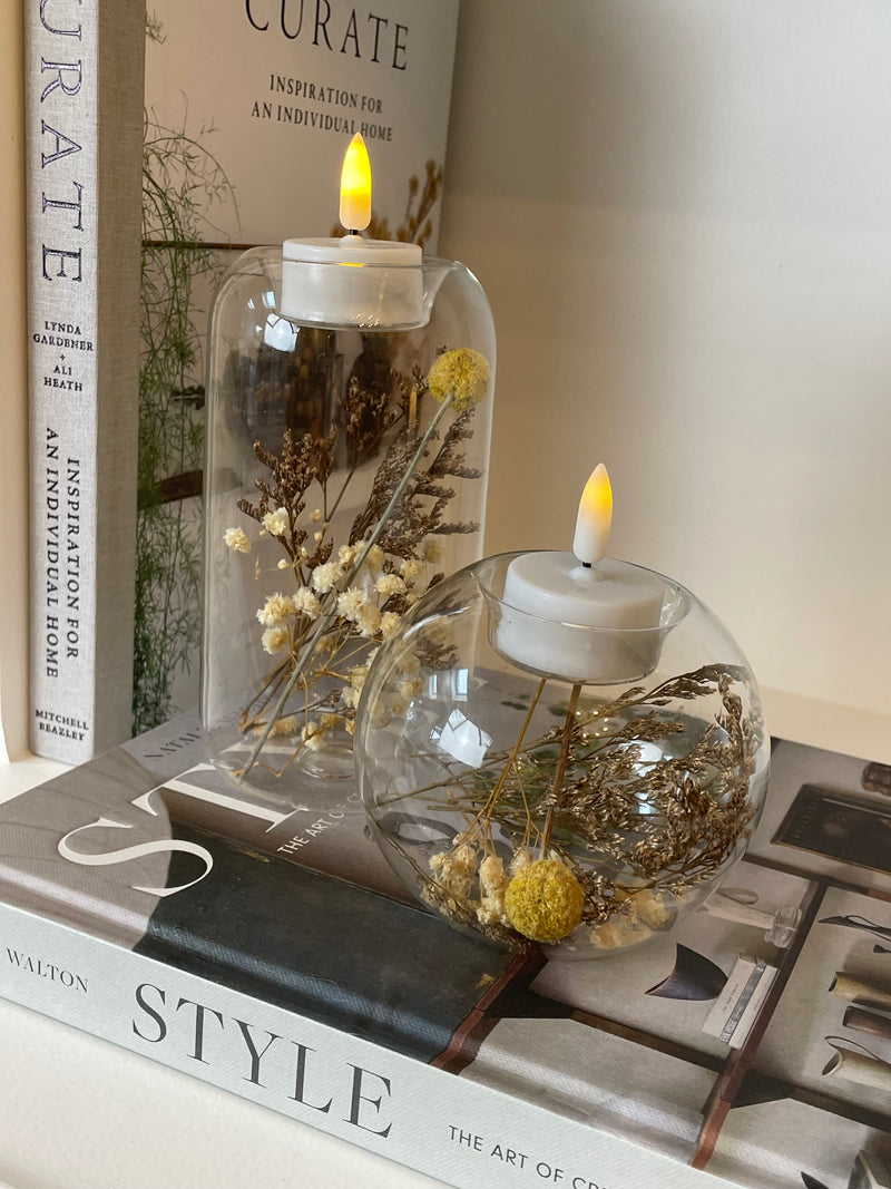 Round glass candle holder filled with dried flowers