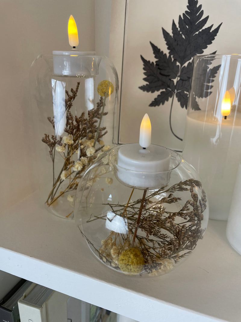 Round glass candle holder filled with dried flowers