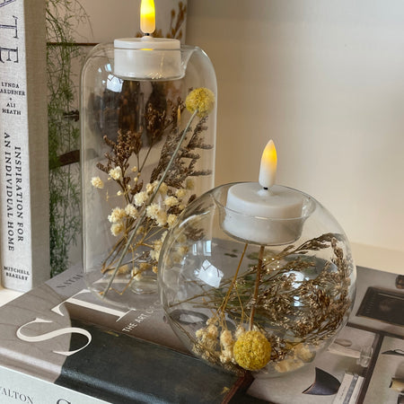 Round glass candle holder filled with dried flowers