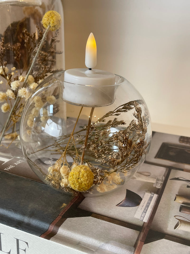 Round glass candle holder filled with dried flowers
