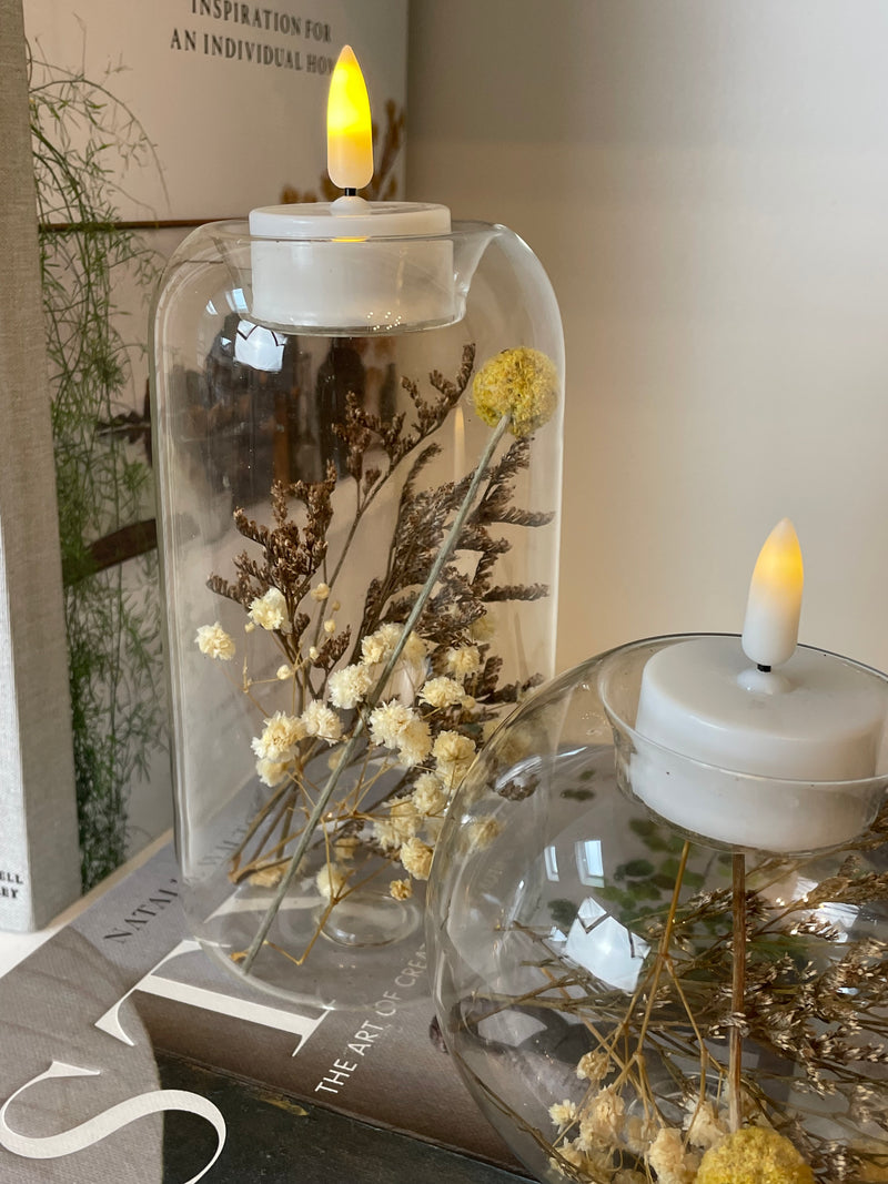 Round glass candle holder filled with dried flowers